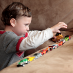 Child playing with assorted matchbox car toys on sofa