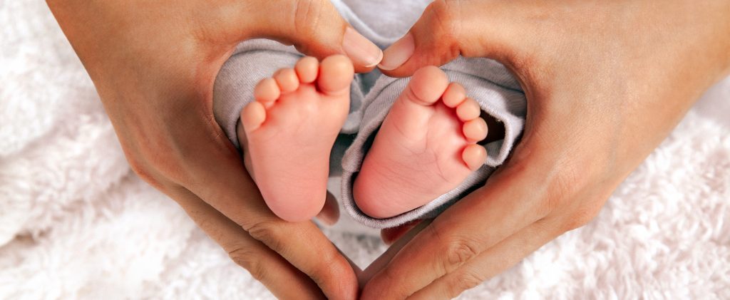 Baby's Feet In Heart Shaped Hands