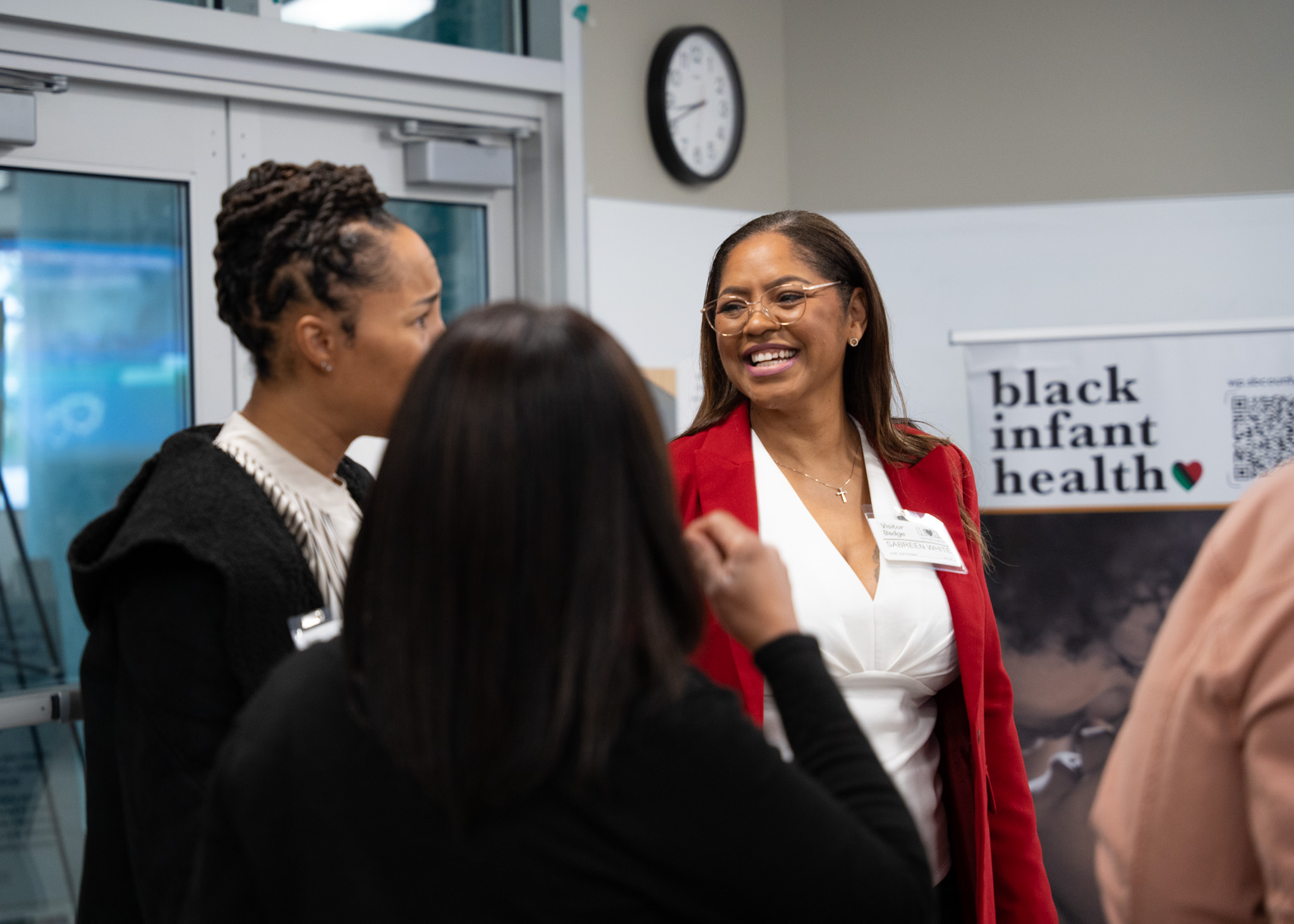 A woman smiles in the direction of the two women she is speaking to.