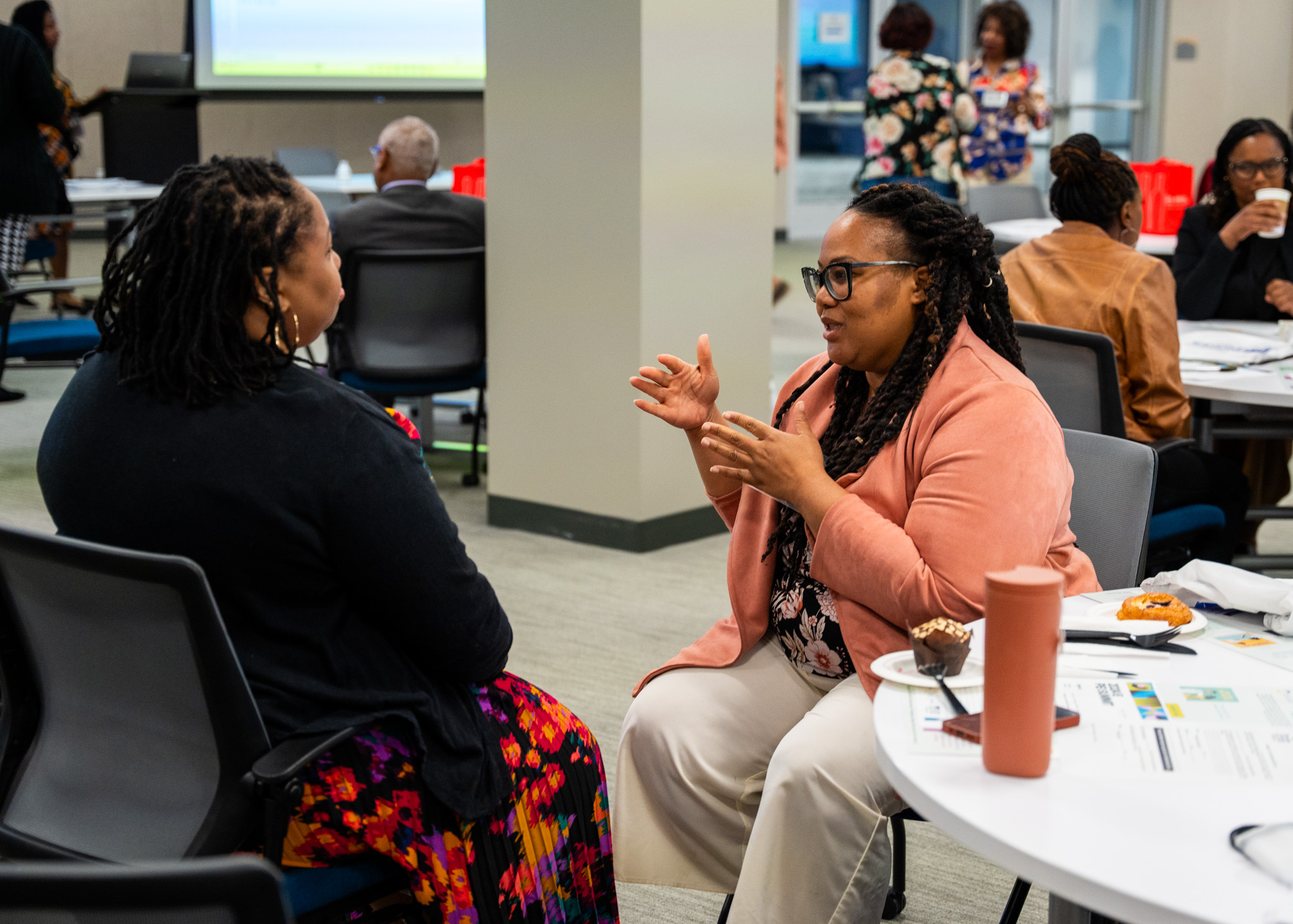 Two women talking sitting down at a table at the 2024 Perinatal Equity Initiative (PEI) Provider and Community Summit