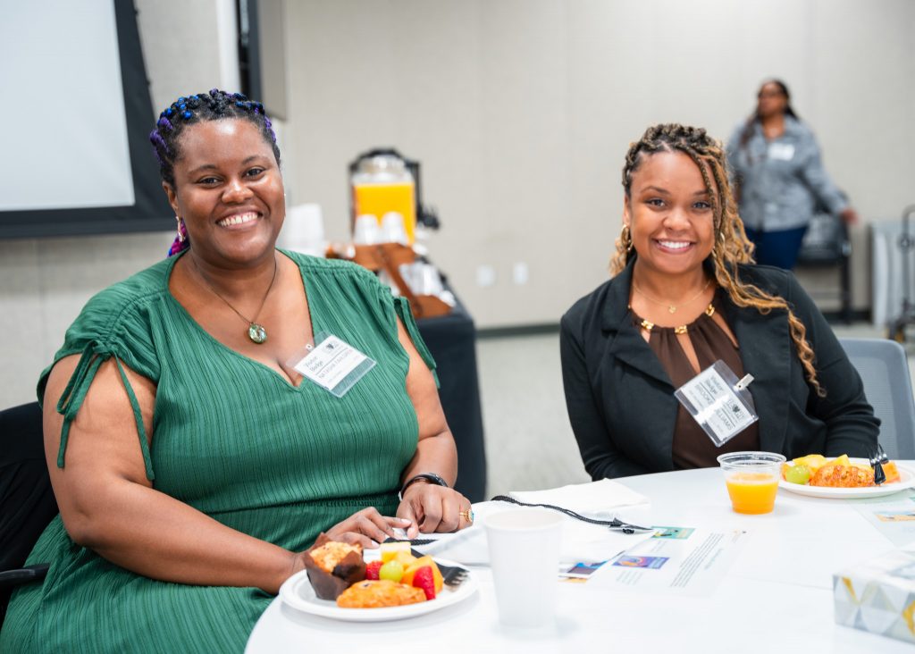 Two women who attended the event pose for a photo while seated at their table.