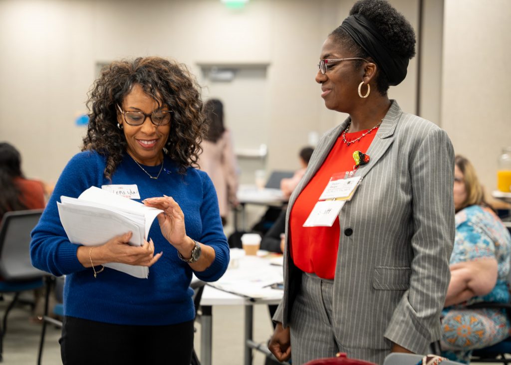 Women handling forms to other women at 2024 Perinatal Equity Initiative (PEI) Provider and Community Summit