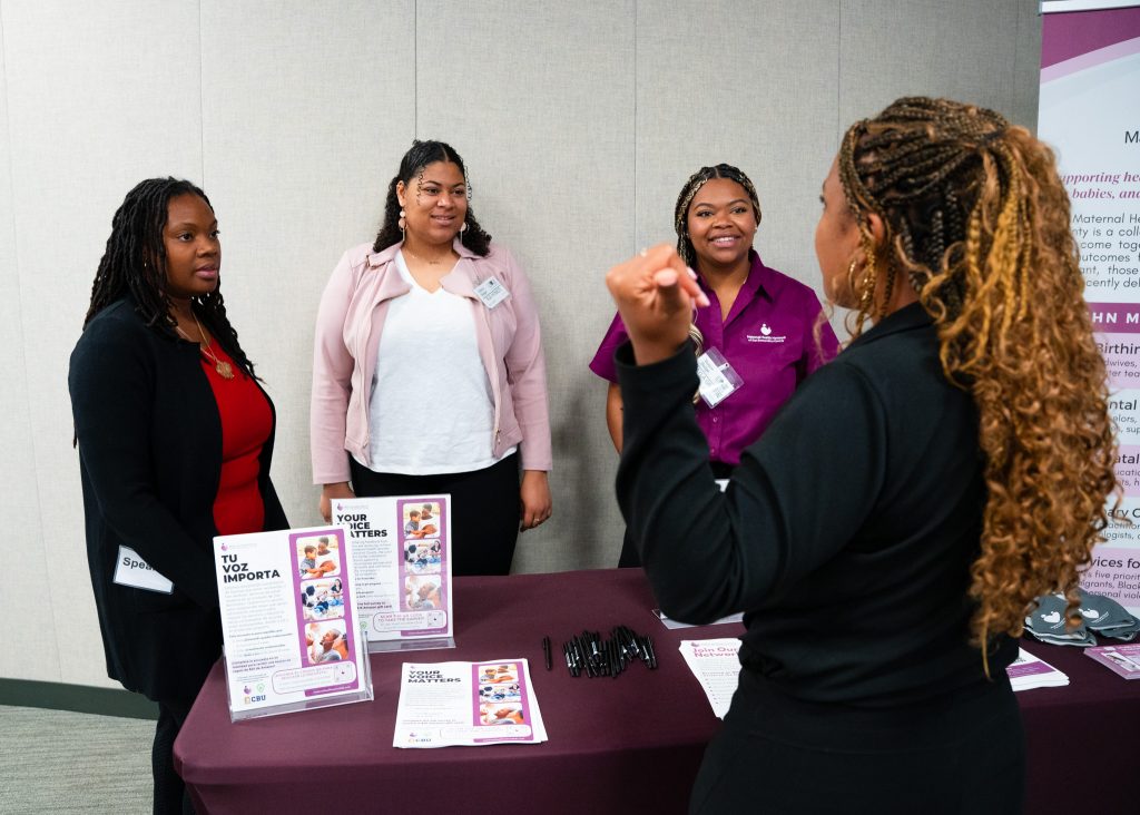 Four women at a 2024 Perinatal Equity Initiative (PEI) Provider and Community Summit stand