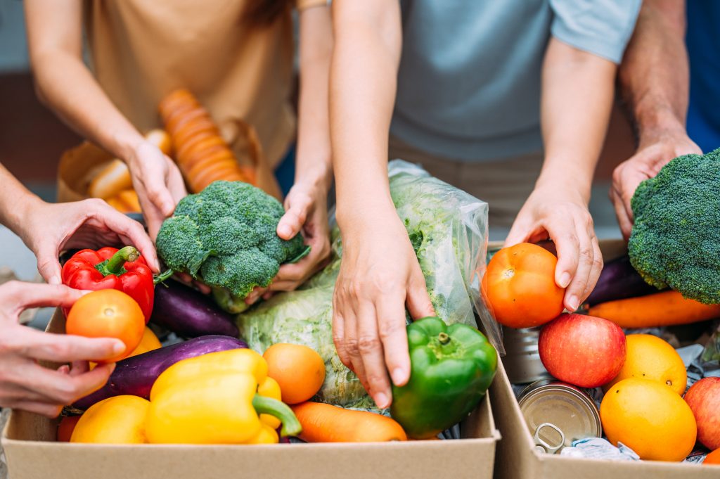People placing produce in food box